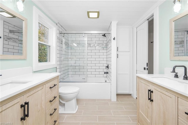 bathroom with enclosed tub / shower combo, two vanities, a sink, and toilet