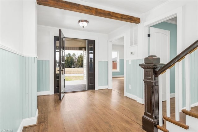 entrance foyer featuring hardwood / wood-style flooring, a wainscoted wall, stairs, beamed ceiling, and crown molding