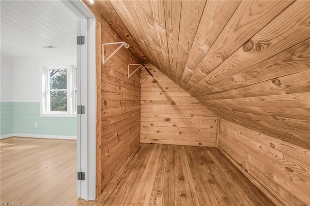 additional living space with wooden ceiling, wooden walls, and wood finished floors