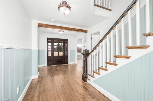 foyer with wood finished floors, baseboards, stairs, wainscoting, and crown molding