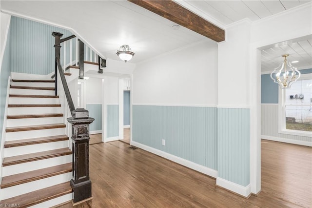 interior space featuring ornamental molding, beam ceiling, a wainscoted wall, and wood finished floors