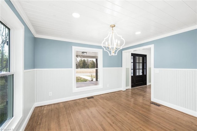 unfurnished dining area with a wainscoted wall, visible vents, and wood finished floors