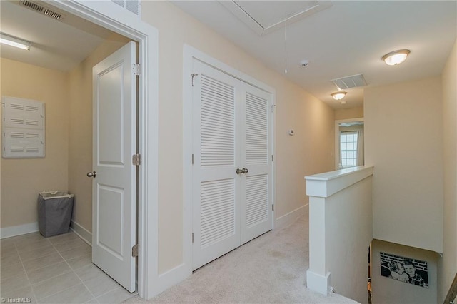 hallway with an upstairs landing, visible vents, and attic access