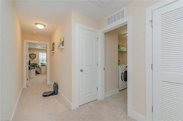 corridor featuring baseboards, visible vents, washer / clothes dryer, and light carpet