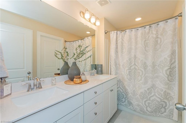 bathroom featuring double vanity, visible vents, tile patterned floors, and a sink