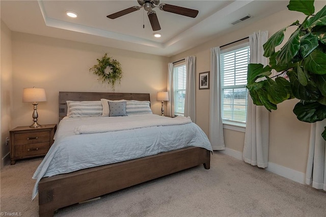 carpeted bedroom with visible vents, baseboards, ceiling fan, a tray ceiling, and recessed lighting