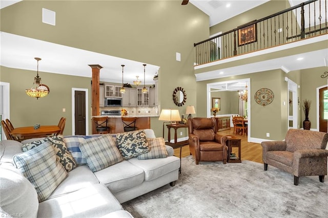 7821 Charles Place Dr, Kernersville, NC 27284 - living room with a chandelier, light wood finished floors, a towering ceiling, and ornate columns