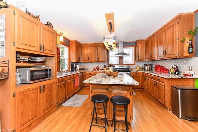 kitchen with a breakfast bar, a center island, plenty of natural light, and appliances with stainless steel finishes