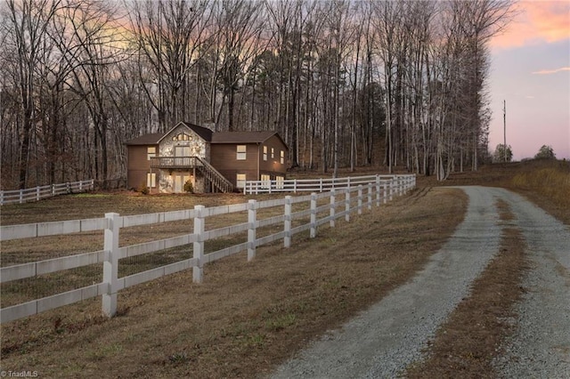 view of front facade featuring driveway, stairway, and fence