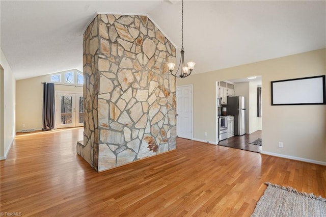 unfurnished dining area with high vaulted ceiling, light wood-style flooring, a chandelier, and baseboards