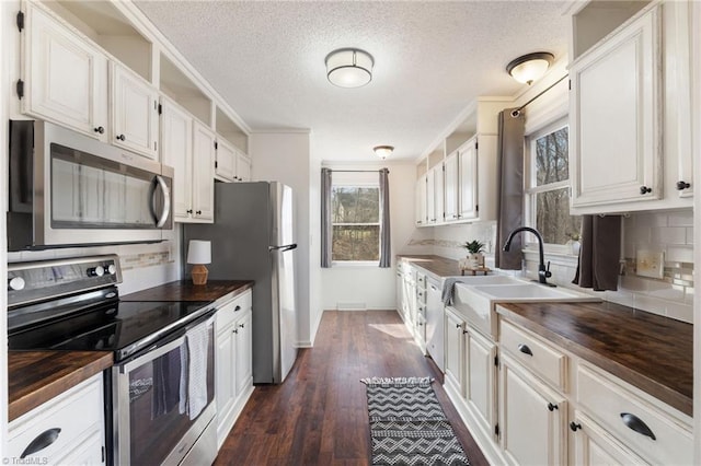 kitchen with stainless steel appliances, dark wood-style flooring, wood counters, and white cabinetry