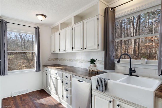 kitchen with a sink, visible vents, stainless steel dishwasher, backsplash, and dark wood finished floors