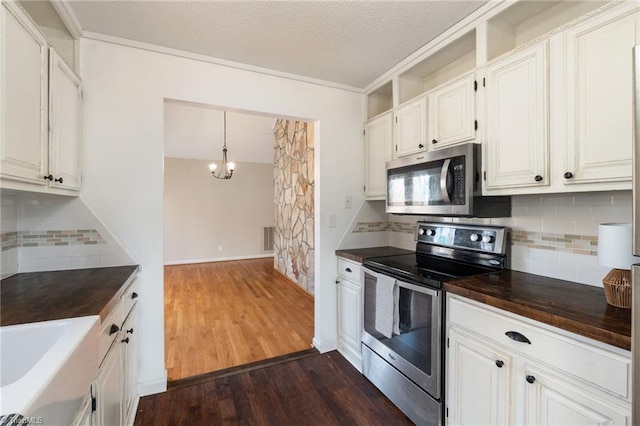 kitchen with dark wood-style flooring, stainless steel appliances, visible vents, a textured ceiling, and butcher block countertops