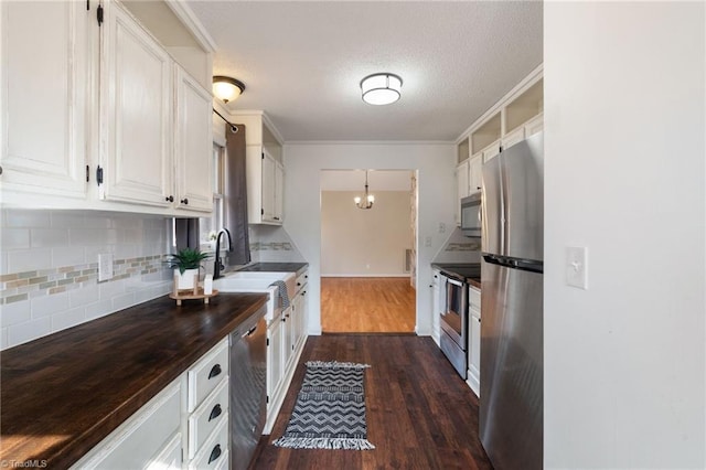 kitchen featuring stainless steel appliances, dark wood-type flooring, a sink, white cabinets, and crown molding