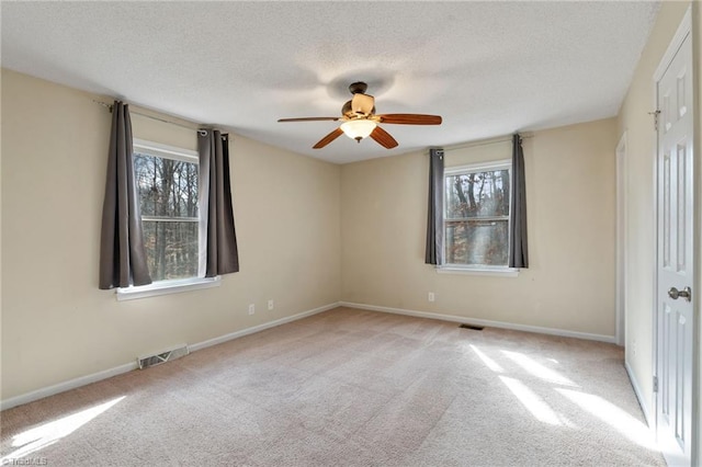 spare room featuring a textured ceiling, carpet flooring, and visible vents