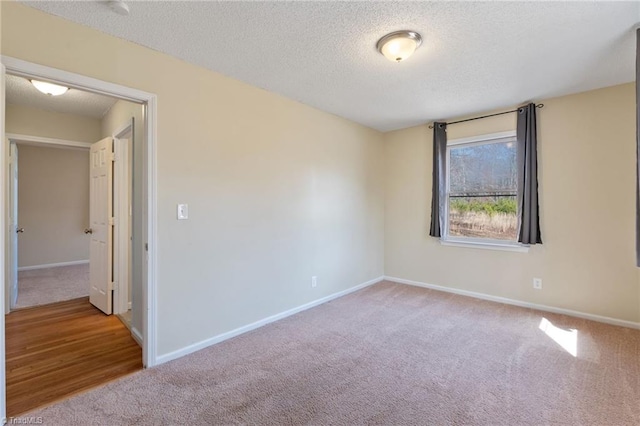 unfurnished room with a textured ceiling, carpet, and baseboards