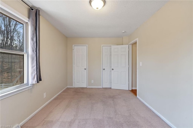 unfurnished bedroom with carpet floors, baseboards, and a textured ceiling