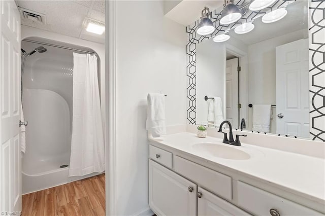 full bathroom with visible vents, curtained shower, wood finished floors, and vanity