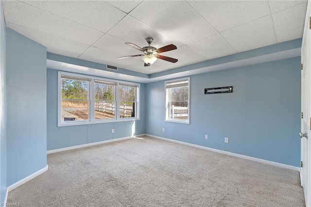 carpeted spare room featuring a ceiling fan, baseboards, visible vents, and a drop ceiling