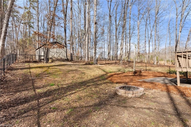 view of yard with an outdoor fire pit, fence, and an outdoor structure