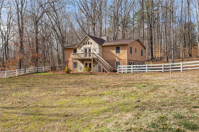 rustic home with stairway, a deck, fence private yard, stone siding, and a front lawn