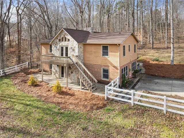 view of front of home featuring a fenced front yard, brick siding, stairway, stone siding, and driveway