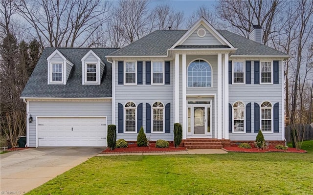 greek revival house featuring a front lawn, an attached garage, driveway, and a shingled roof