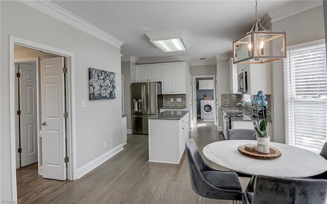 kitchen featuring white cabinets, appliances with stainless steel finishes, washer / clothes dryer, and crown molding