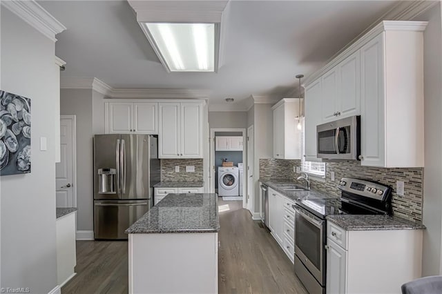 kitchen featuring washer / dryer, a sink, white cabinets, appliances with stainless steel finishes, and a center island