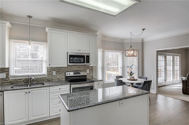 kitchen featuring a sink, appliances with stainless steel finishes, white cabinetry, crown molding, and backsplash