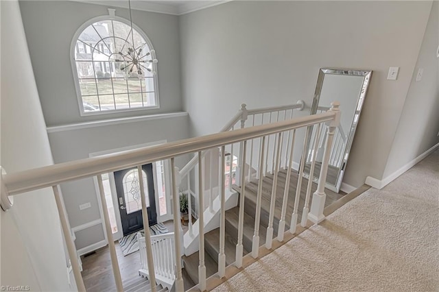 stairs featuring wood finished floors, baseboards, and a chandelier