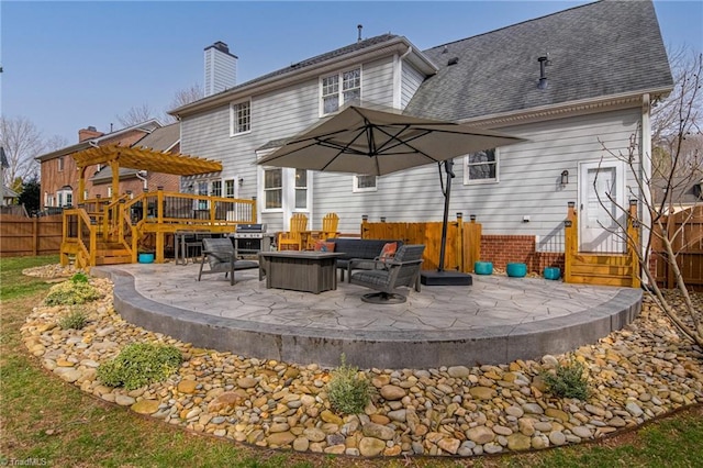 rear view of property featuring a patio, fence, a wooden deck, a pergola, and a chimney