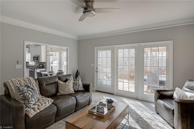 living area with light carpet, crown molding, and ceiling fan with notable chandelier