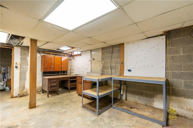 basement with a workshop area and a paneled ceiling