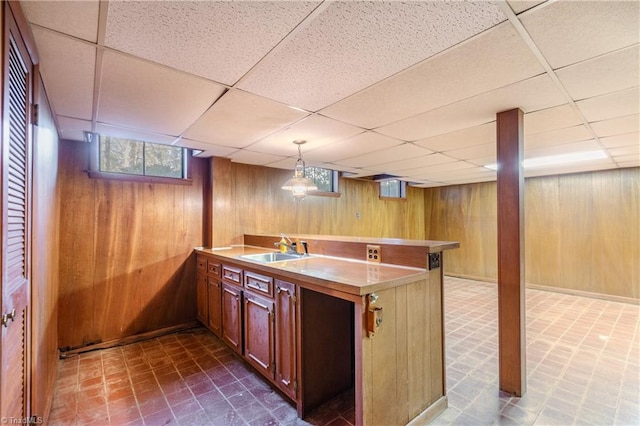 bar featuring pendant lighting, a paneled ceiling, wooden walls, and sink