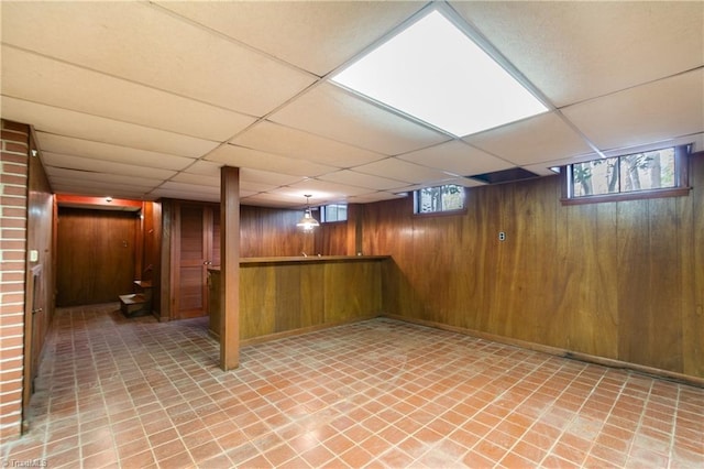 basement with a paneled ceiling and wooden walls