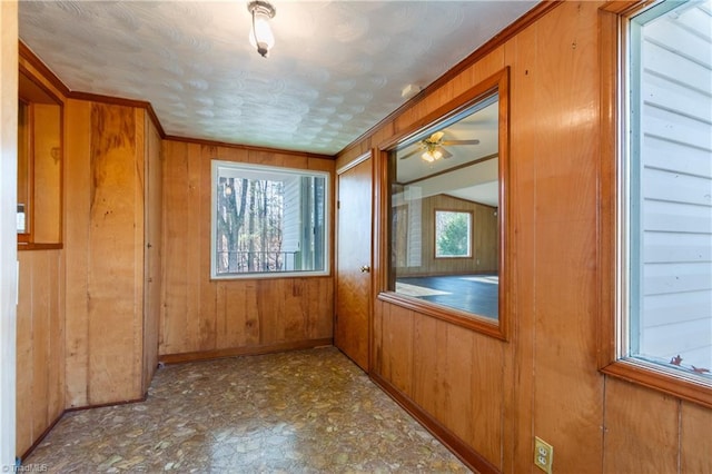 interior space with ceiling fan and wooden walls