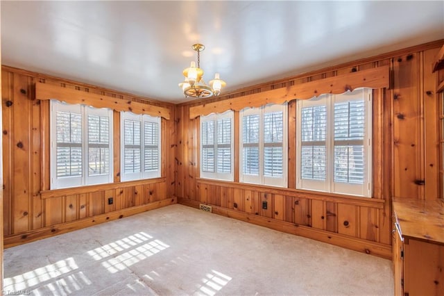 unfurnished dining area with a wealth of natural light, a chandelier, and wood walls