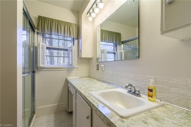 bathroom with tile patterned floors, vanity, a shower with door, and tasteful backsplash