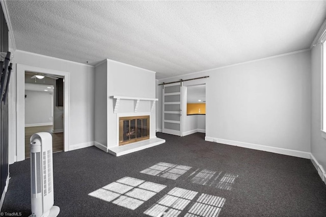 3231 Arlington Dr, Winston-Salem, NC 27103 - unfurnished living room featuring a textured ceiling, crown molding, a barn door, dark colored carpet, and a glass covered fireplace