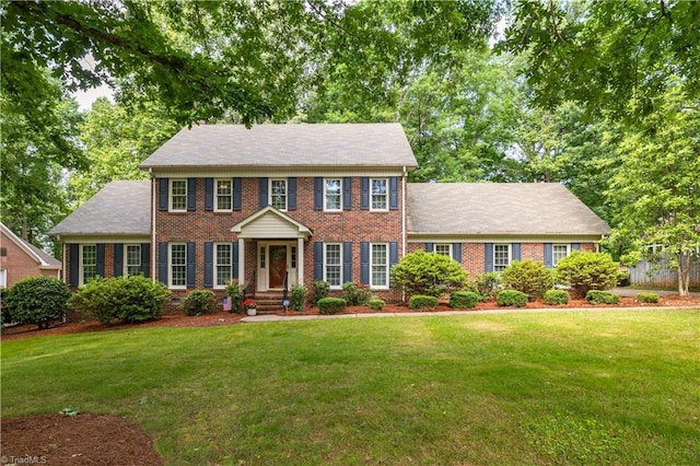 colonial inspired home featuring a front yard and brick siding