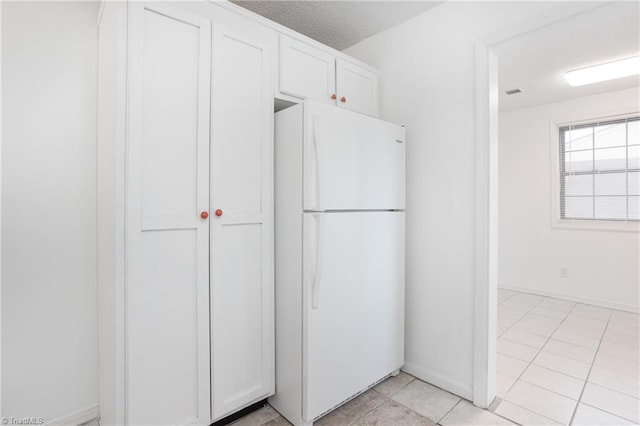 kitchen with white cabinetry, white fridge, and light tile patterned floors