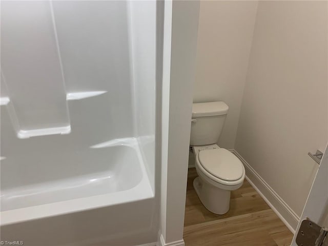 bathroom with a bath, wood-type flooring, and toilet