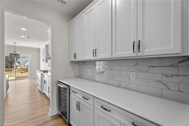 271 Redland Rd, Advance, NC 27006 - kitchen with wine cooler, decorative backsplash, light countertops, white cabinetry, and light wood finished floors