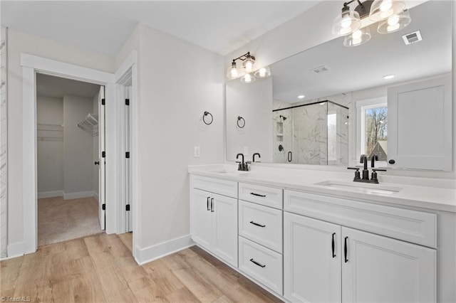 271 Redland Rd, Advance, NC 27006 - bathroom featuring a marble finish shower, double vanity, a chandelier, wood finished floors, and a walk in closet