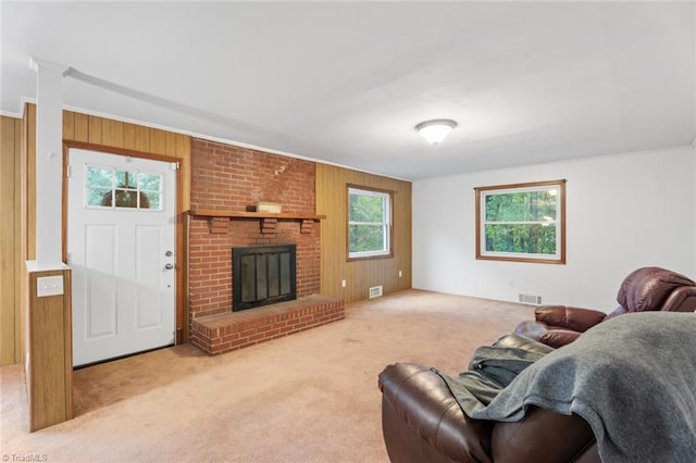 carpeted living room with a brick fireplace and wooden walls