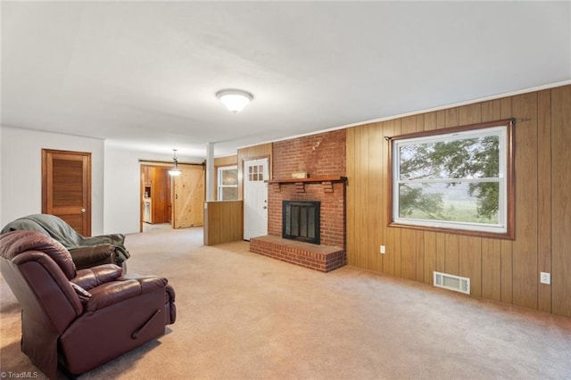 living room with light carpet, wooden walls, and a brick fireplace