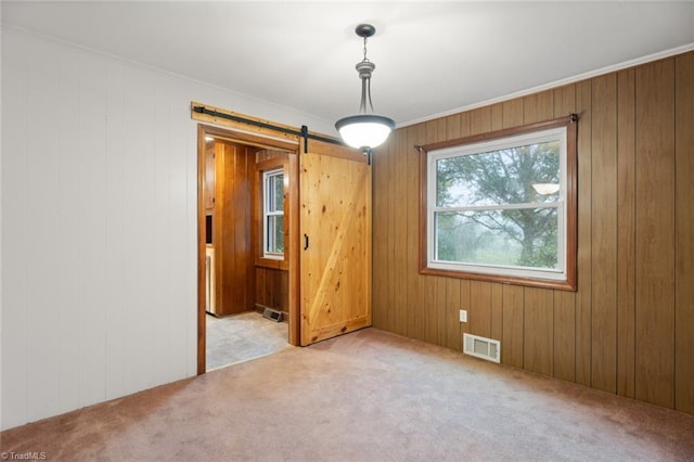 unfurnished room featuring light carpet, wooden walls, and a barn door