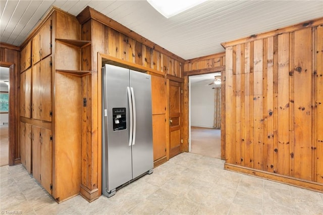 kitchen featuring wood walls, ceiling fan, and stainless steel fridge