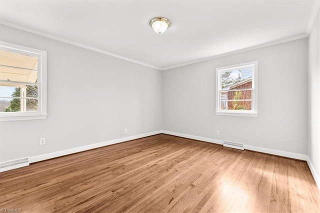 spare room featuring hardwood / wood-style floors, crown molding, and plenty of natural light